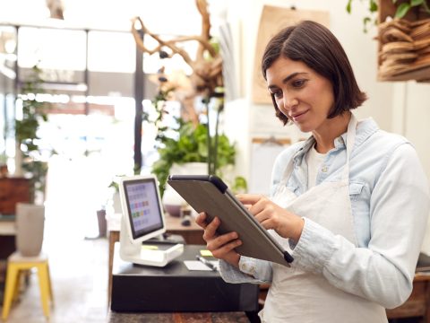 Female,Owner,With,Digital,Tablet,Standing,Behind,Sales,Desk,Of